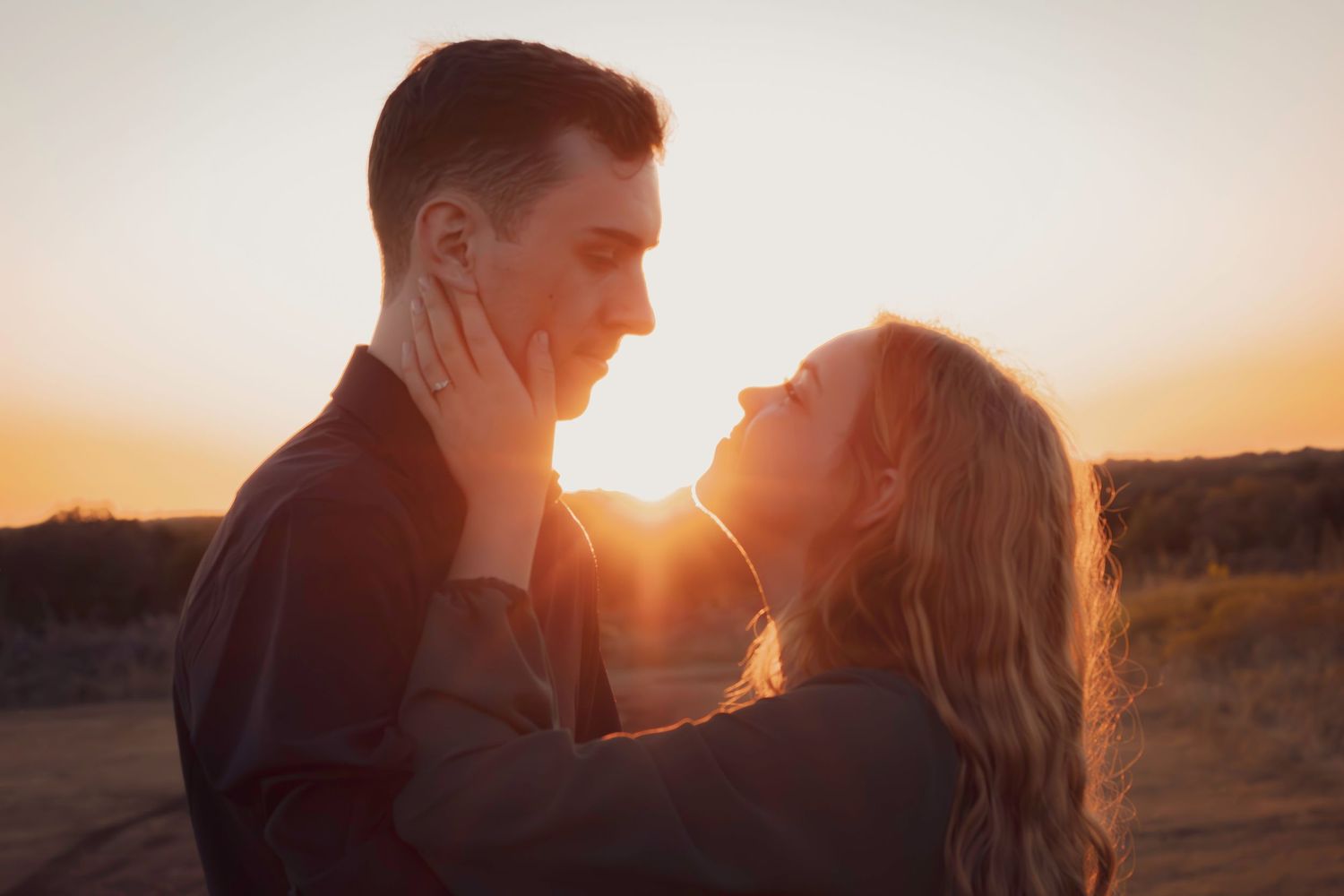 A romantic couple shares an intimate moment in golden sunset light.