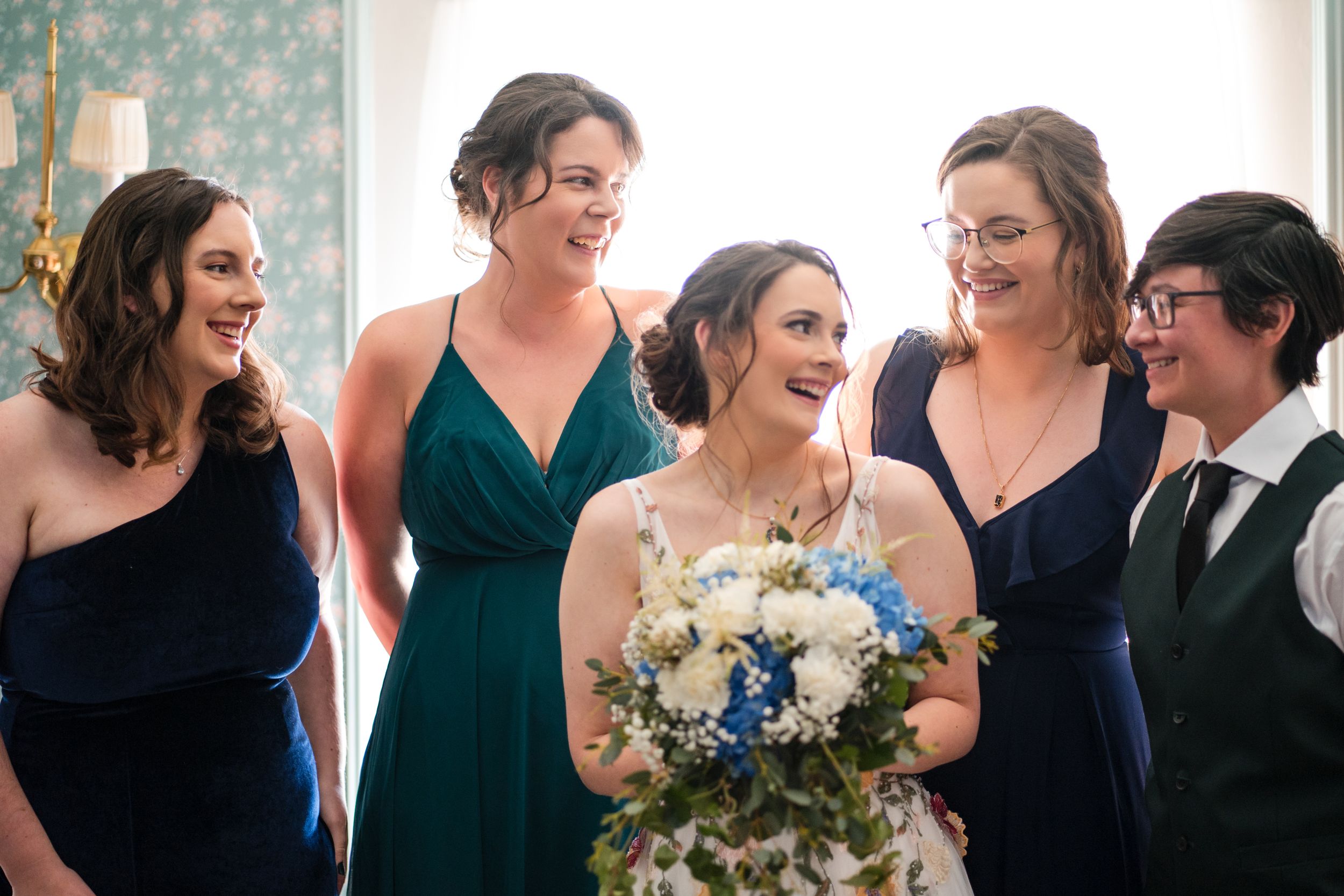 Joyful bridal party sharing a laugh in coordinated navy and emerald dresses.