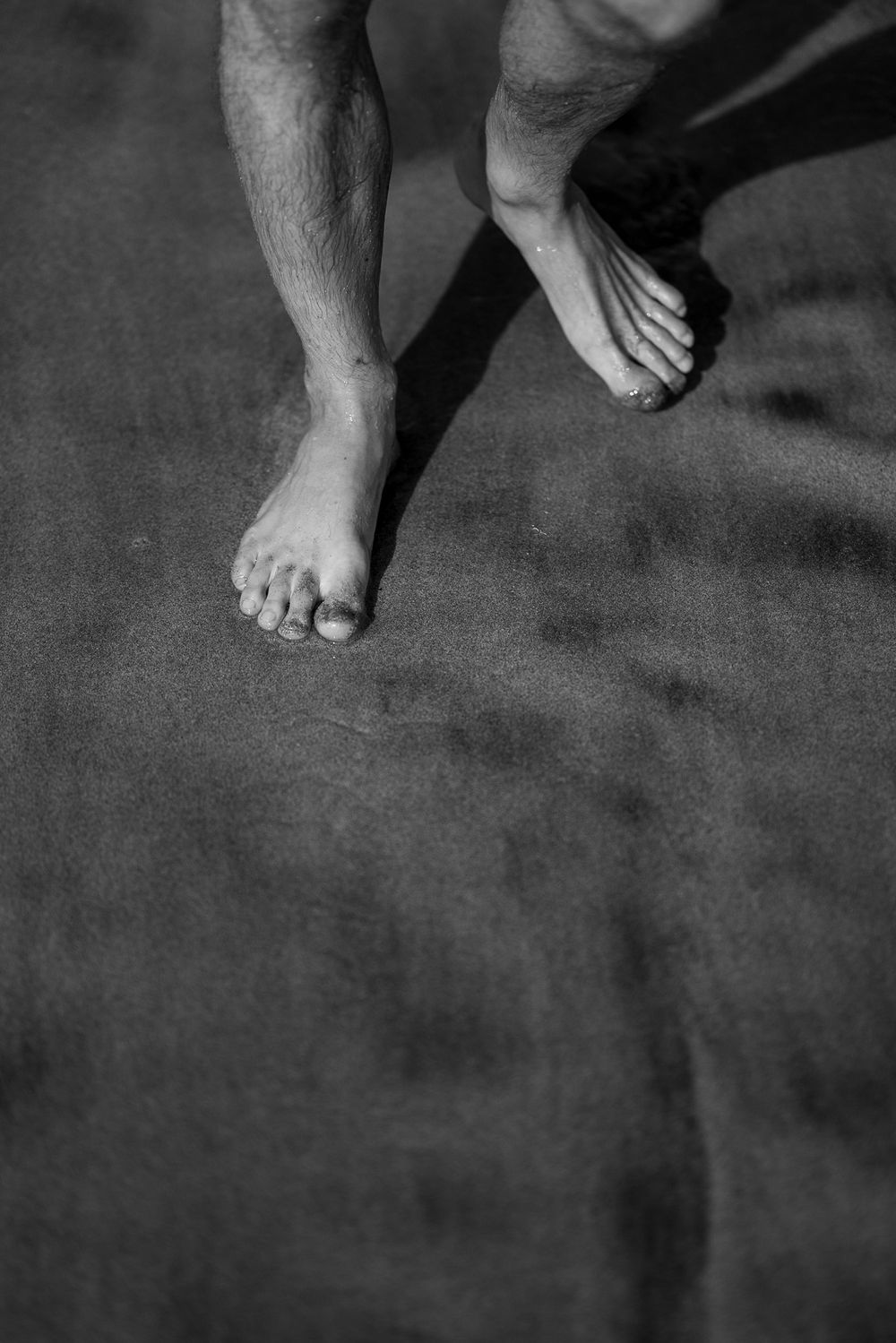 Black and white close-up shot of bare feet on a dark surface.