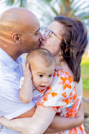 A family shares a tender moment together outdoors on a sunny day.