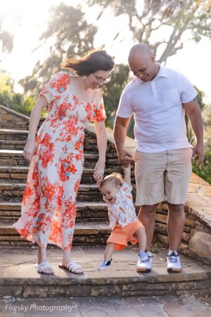 A family walks down stone steps together in a garden setting while holding hands.