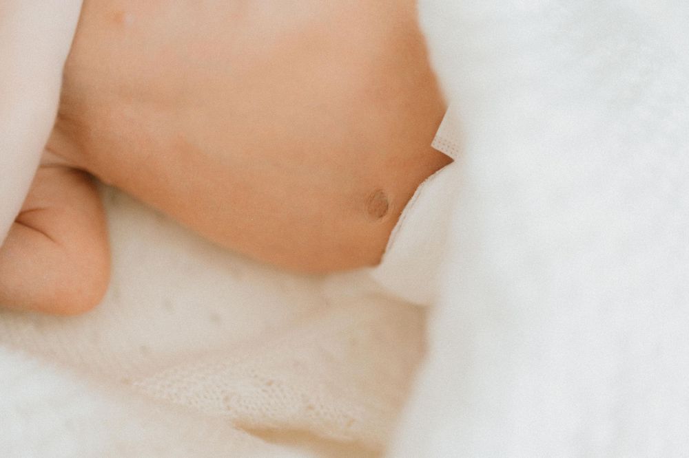Close-up view of newborn baby skin against soft white bedding.