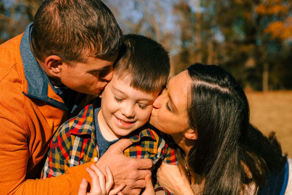 A tender family moment captured outdoors during autumn with warm embraces and smiles.