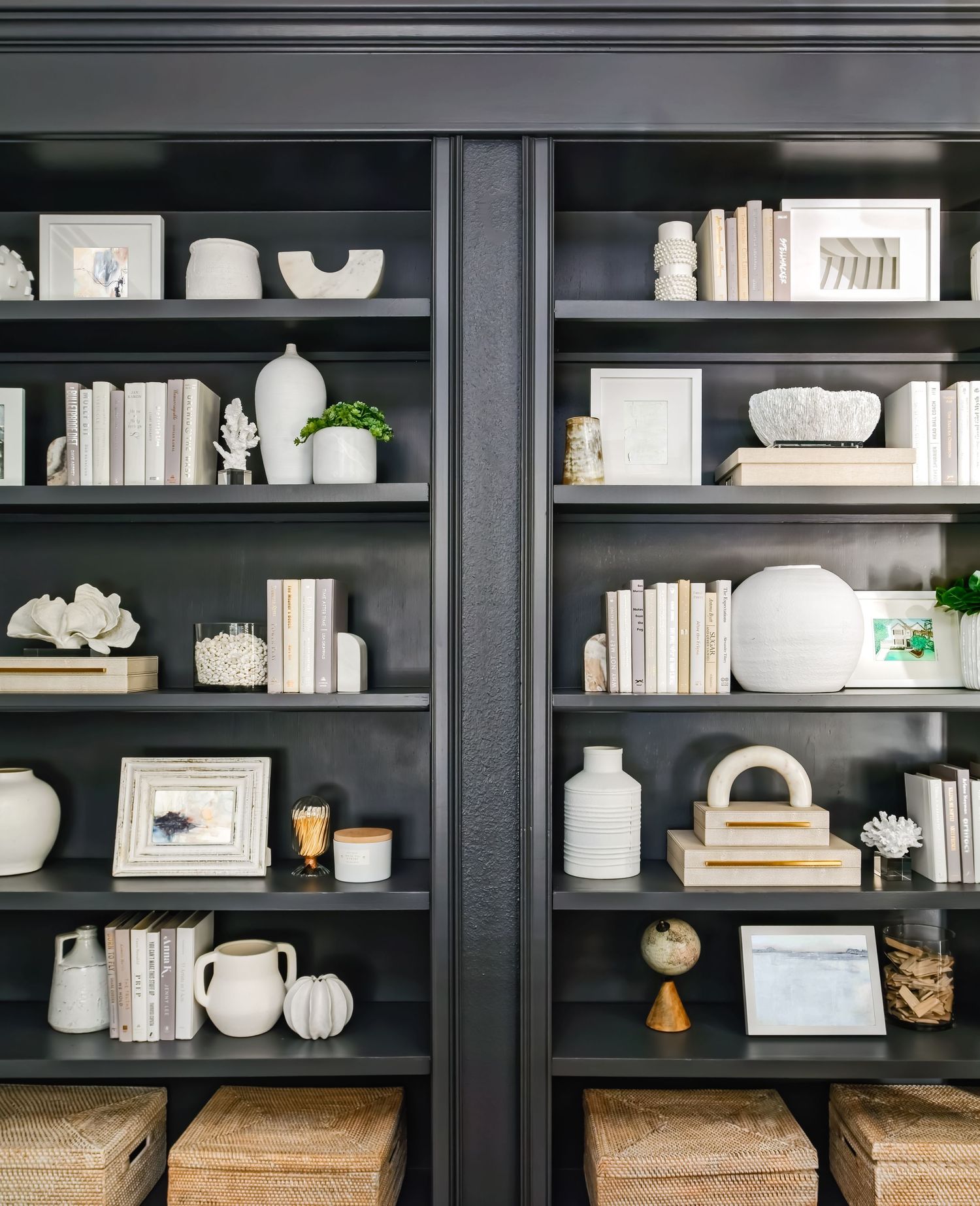 Dark black built-in bookshelves styled with white ceramics, neutral books, and decorative objects.