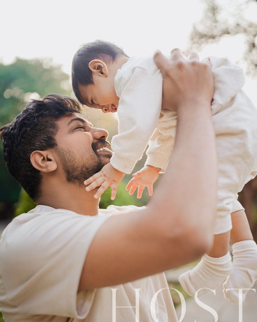 A tender moment between parent and baby captured outdoors with natural lighting, both wearing white.