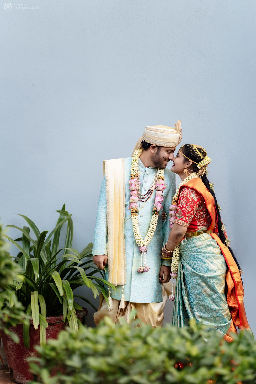 Indian bride and groom in traditional attire sharing a romantic moment, adorned with floral garlands at their wedding ceremony.