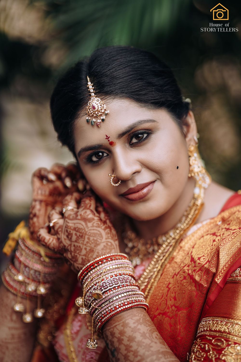 Close-up of bridal jewelry and henna decorated hands with traditional Indian wedding attire.