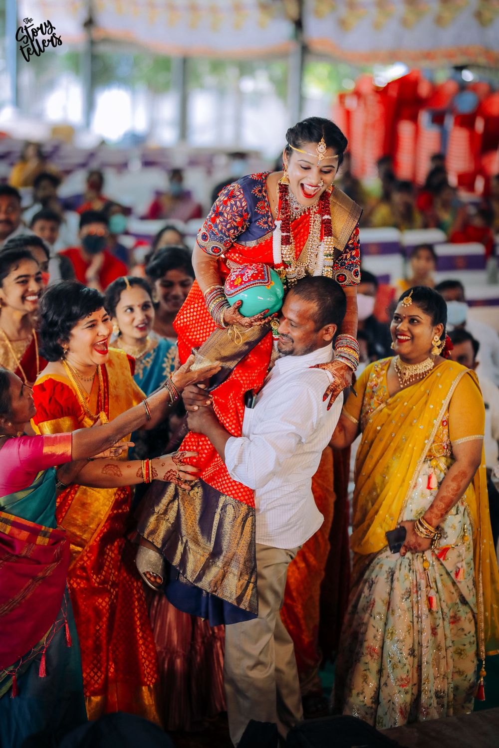 Festive wedding celebration with guests in colorful sarees participating in traditional customs.