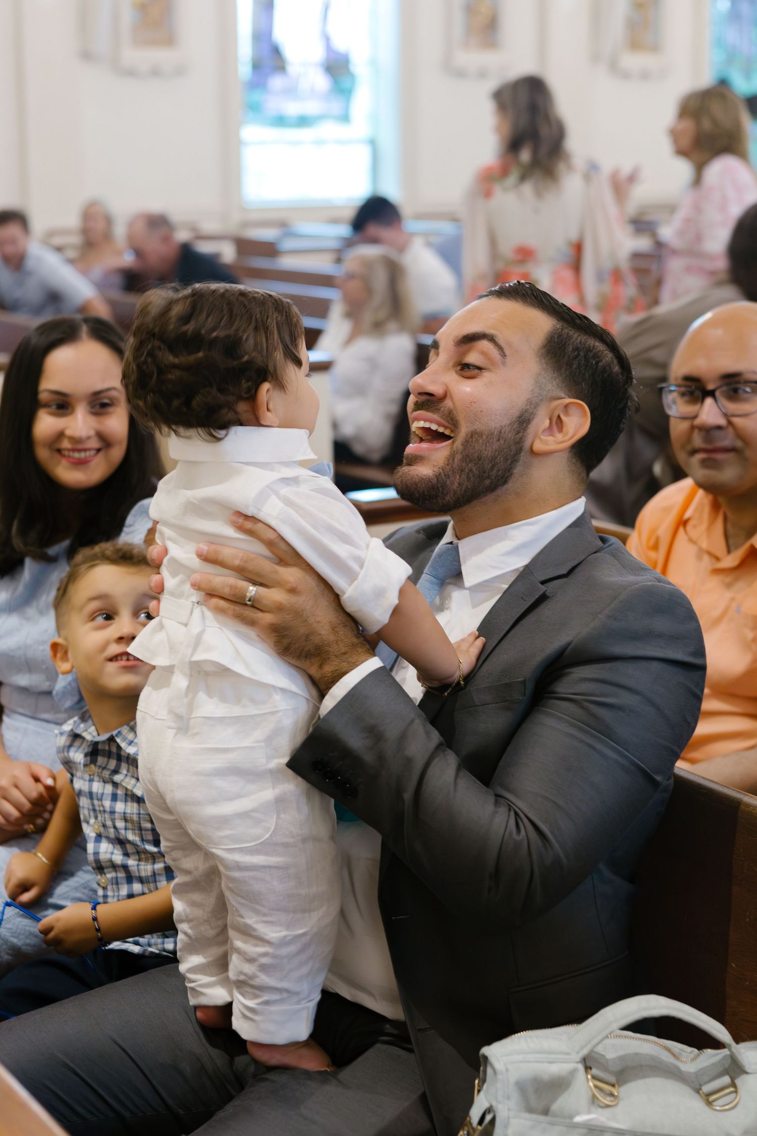 Dad and boy smiling candidly at church by NYC family photographer Paula Ortiz