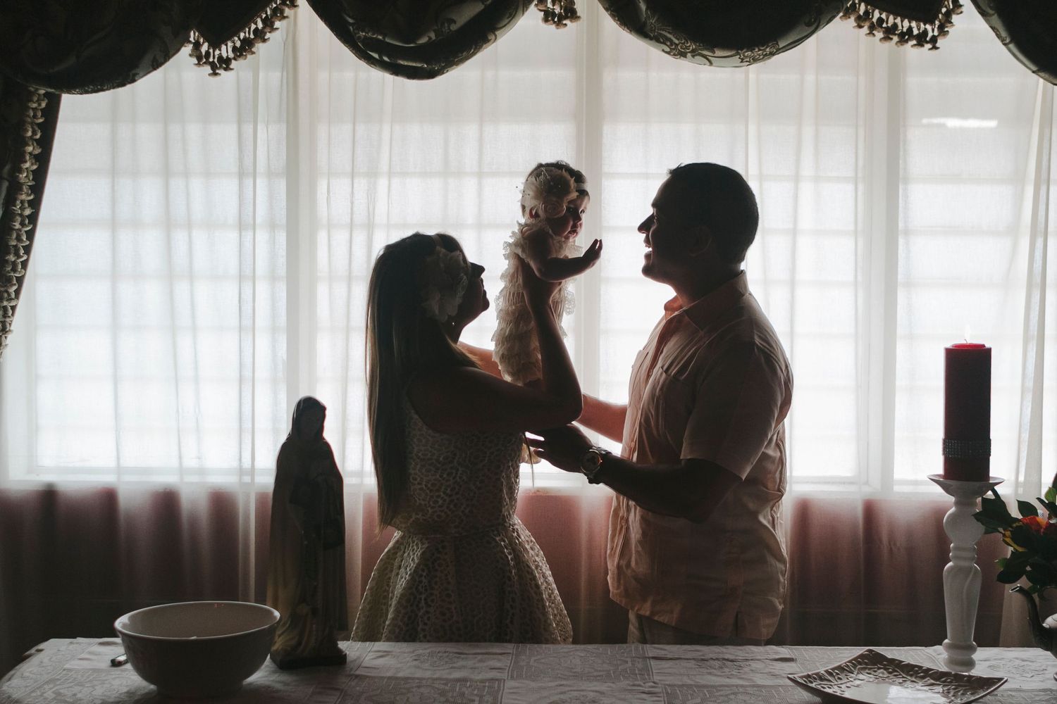 Backlight silhouette of mom, dad, and girl at altar by NYC family photographer Paula Ortiz