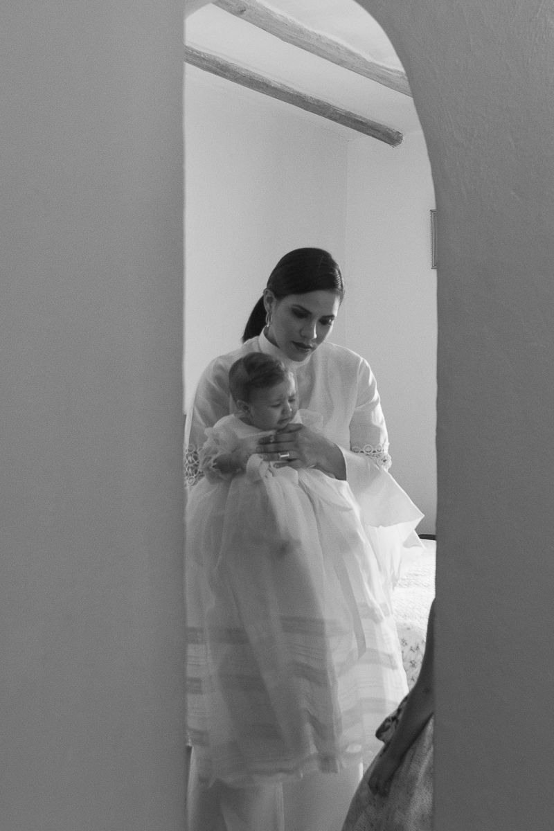 Mom leaving room towards baptism ceremony, captured by NYC family photographer Paula Ortiz.