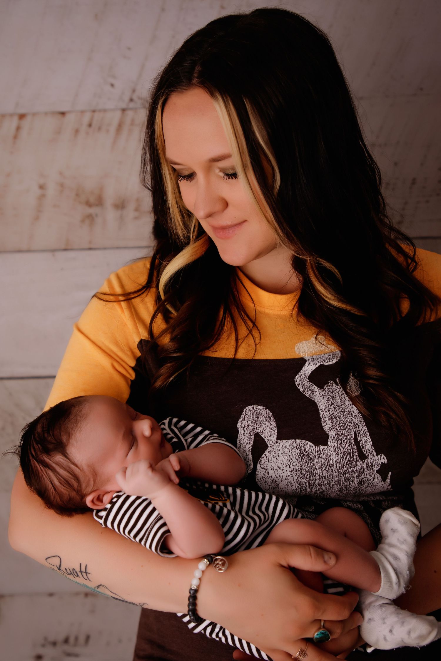 A tender moment captured as parent holds sleeping newborn baby wearing striped onesie.
