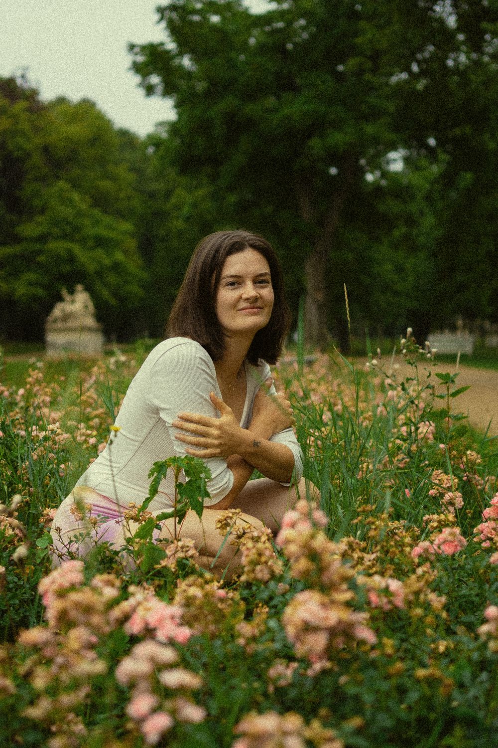 Portrait Fotoshooting Blüherpark Dresden - Sommerliches Bild einer hockenden Frau im Blumenfeld