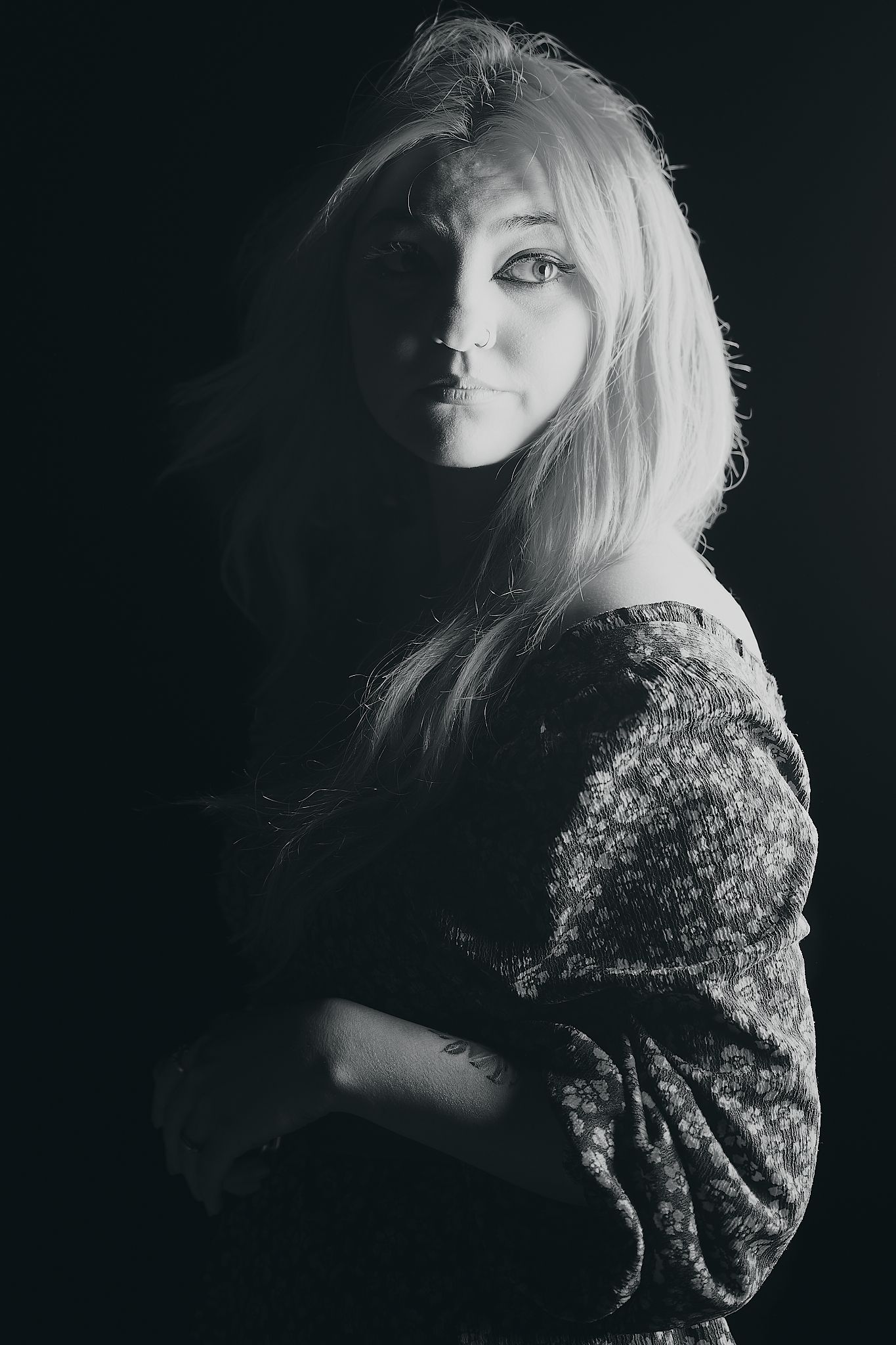 Dramatic black and white portrait with soft lighting and floral patterned clothing.