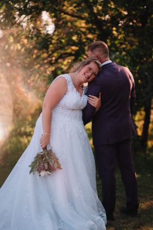 Joyful bride in lace gown laughing with groom during sunset portrait session.