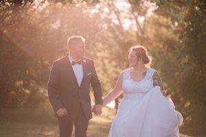 Wedding couple walking hand in hand through a dreamy sunlit outdoor setting.