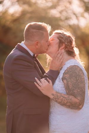 Intimate wedding portrait with couple sharing a tender kiss in warm sunset lighting.