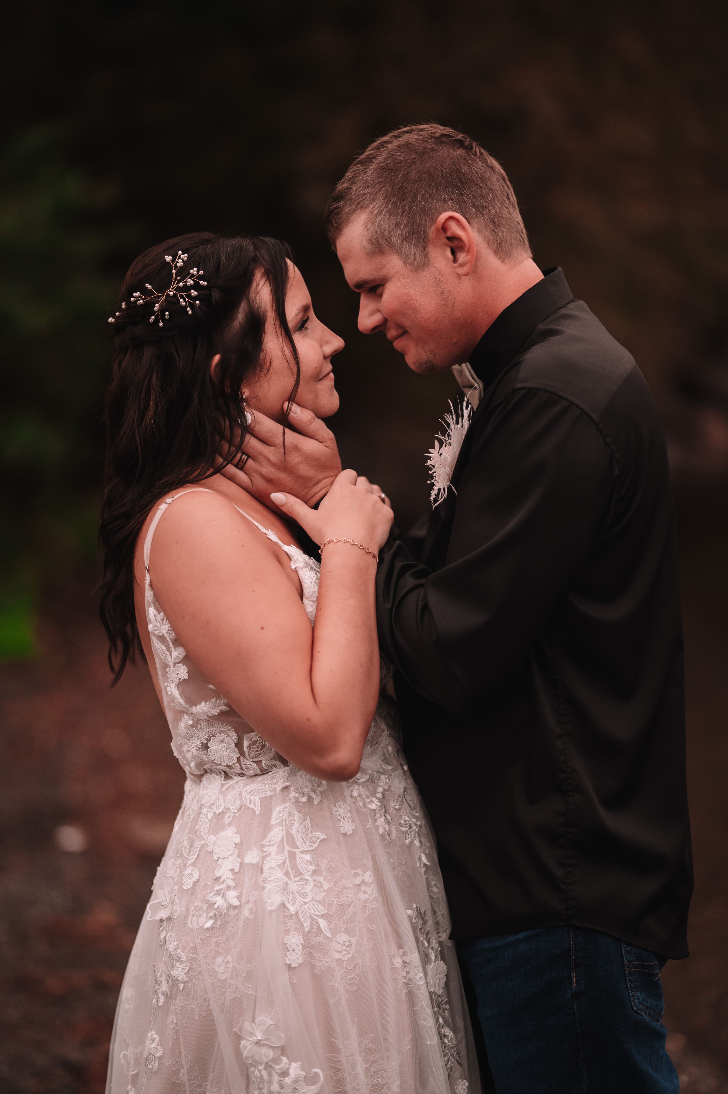 Intimate moment between newlyweds sharing a tender embrace outdoors.