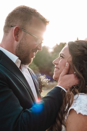 Romantic sunset portrait of newlyweds sharing an intimate moment with sunflare.