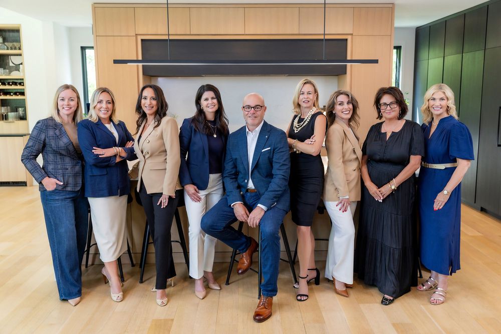 Professional business team in coordinated navy and beige outfits poses together in modern office lobby.