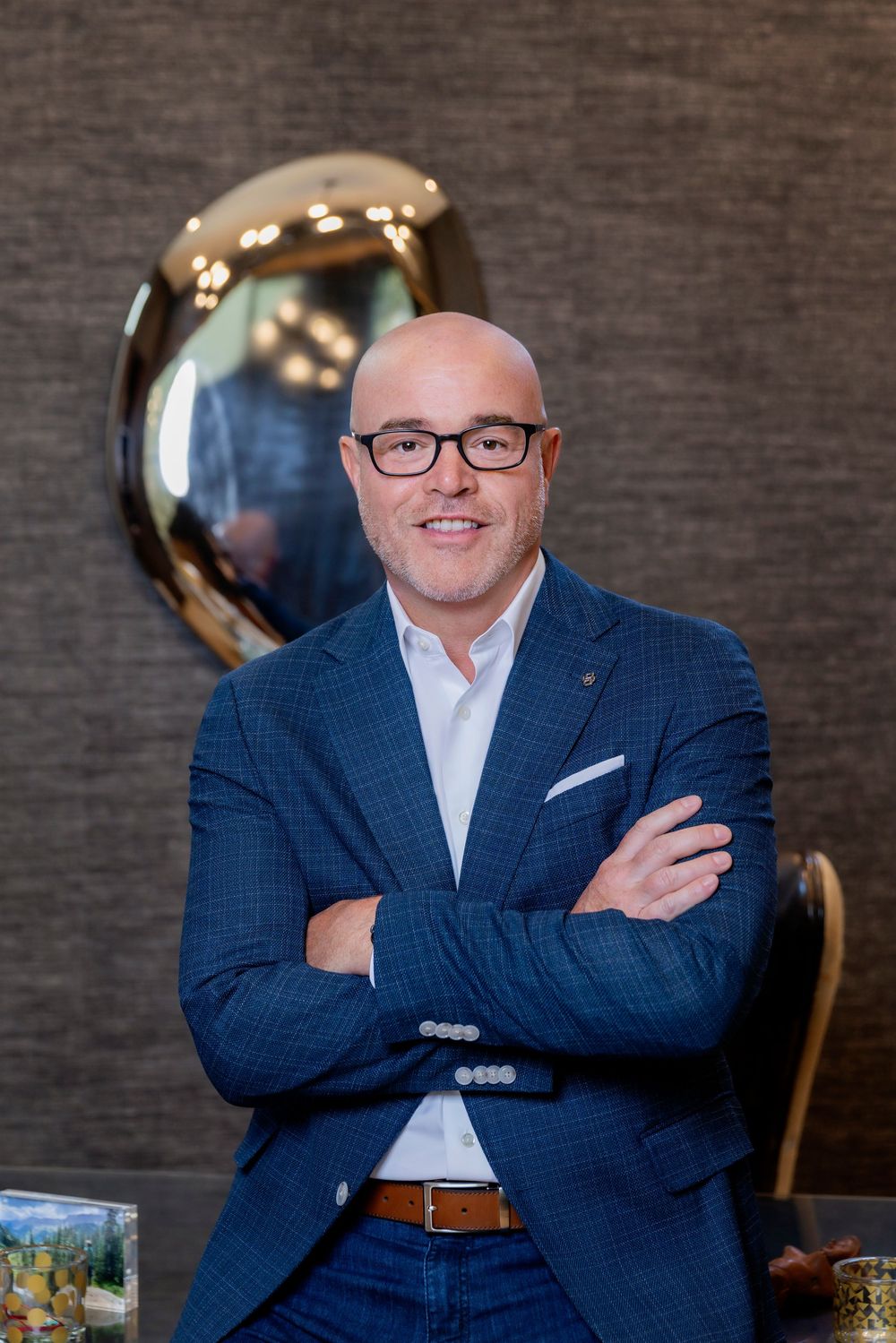 Professional headshot series showing a person in a navy suit and glasses against a textured gray wall.