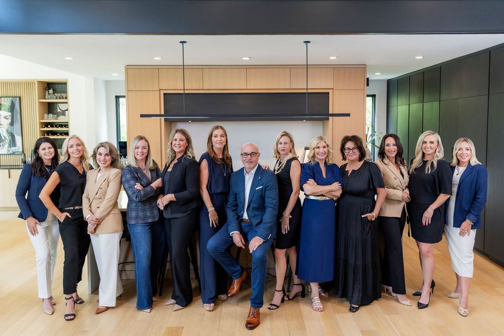 Group of professionals in coordinated blue and black business attire pose together for team photo.