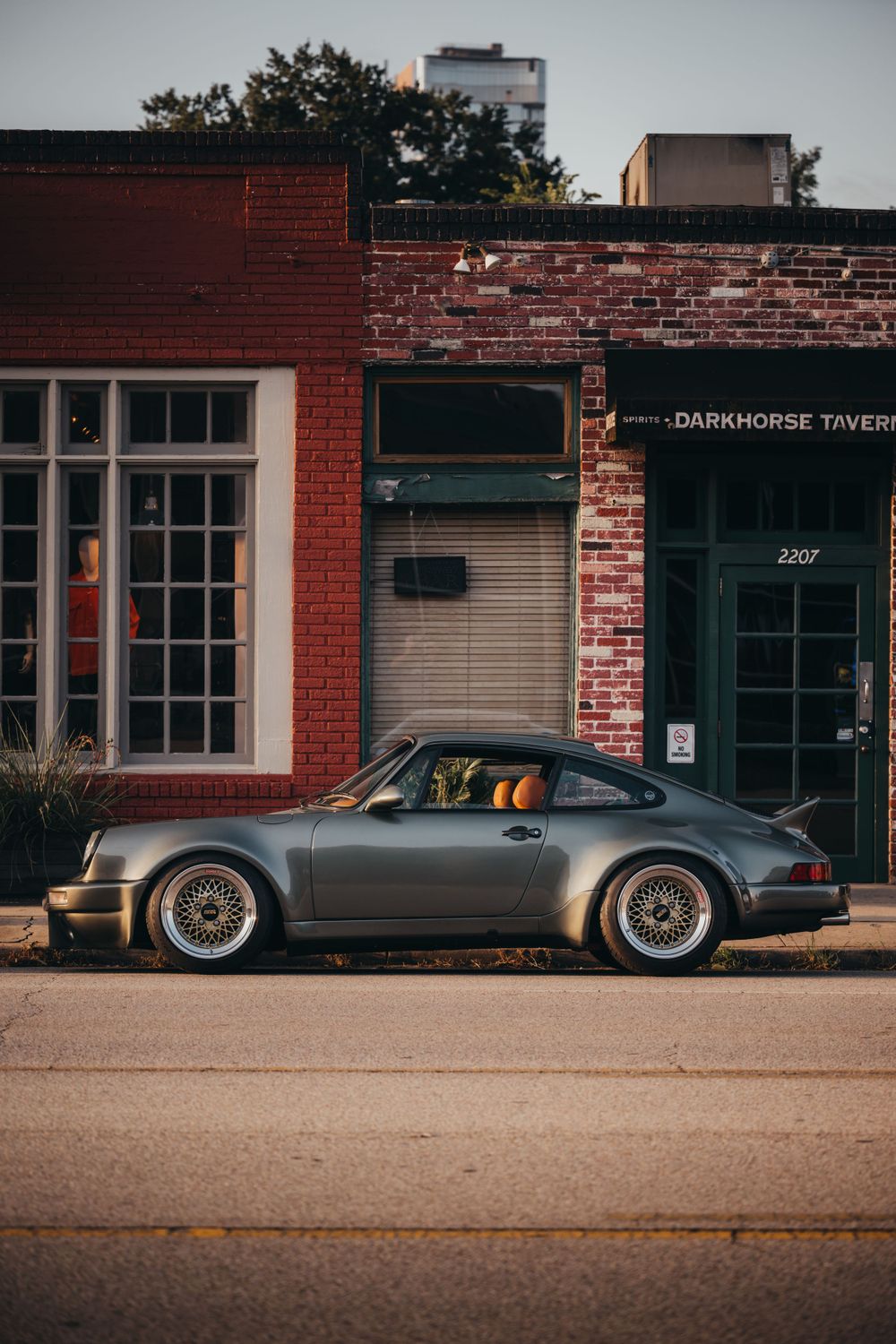 Classic Porsche sports car silhouette parked in front of vintage brick storefronts.