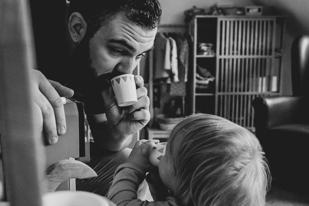Schwarz-Weiß-Bild einer Familienreportage auf dem ein Vater mit kleinem Kind beim Spielen in der Spielküche zu sehen ist.