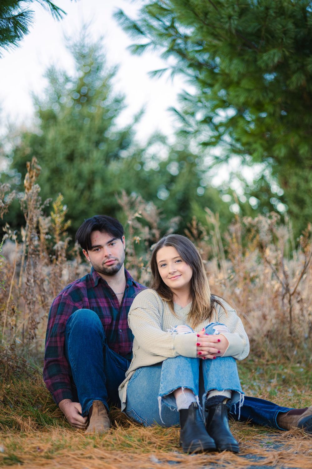 Beautiful portrait of the amazing couple as they sit on the grass and pine needles