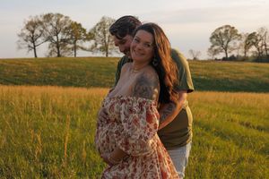 Intimate couple's portrait session in a sun-drenched field during golden hour.