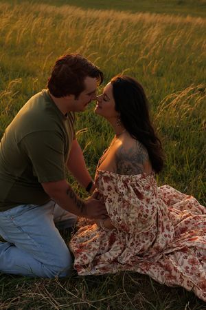 Romantic couple shares tender moment in golden grass field at sunset.