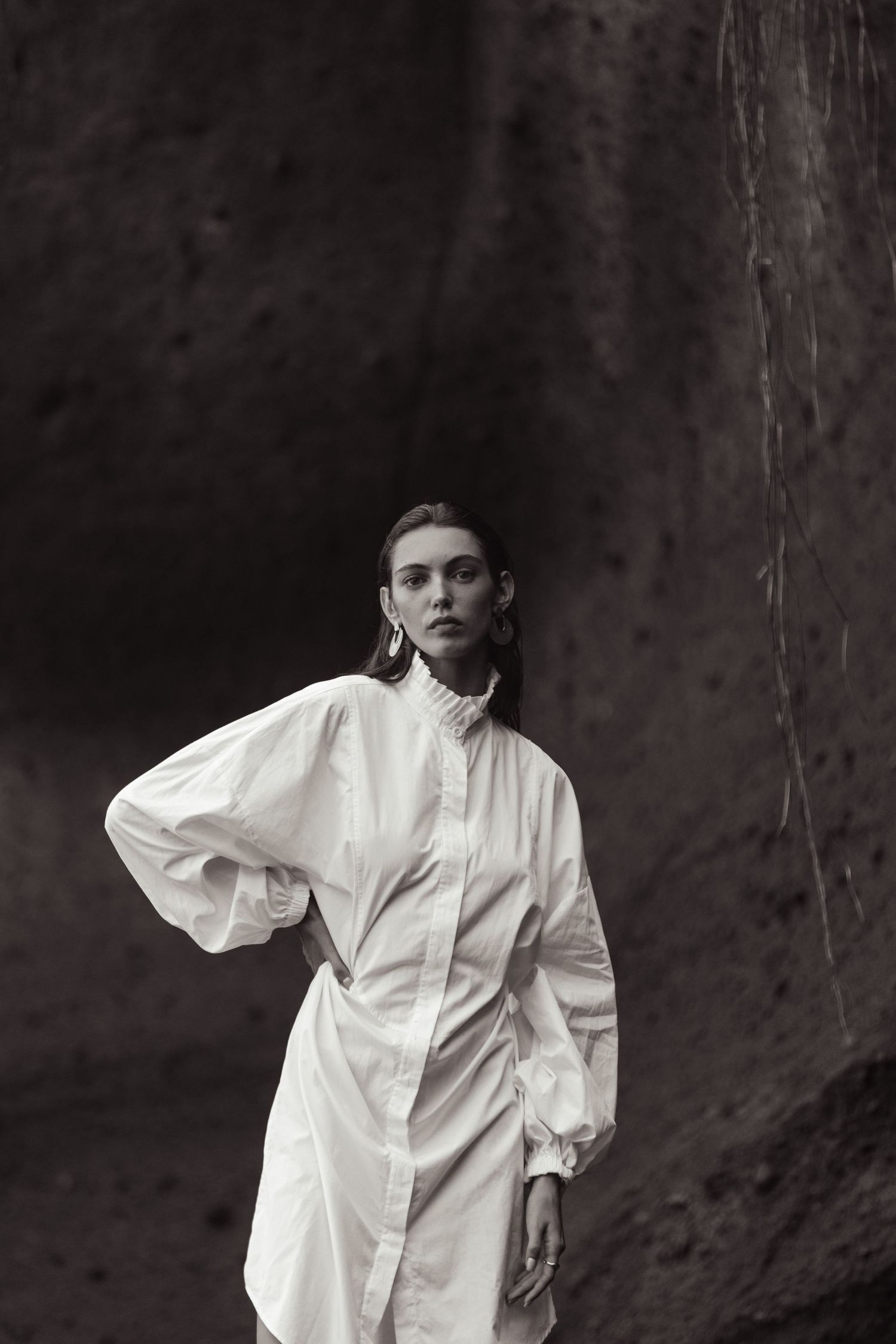 Dramatic black and white fashion portrait against textured wall.