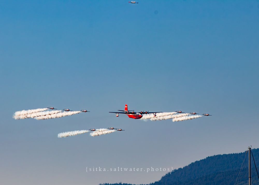 Formation of Hawaii Mars and CF Snowbirds creating white vapor trails during an airshow performance.