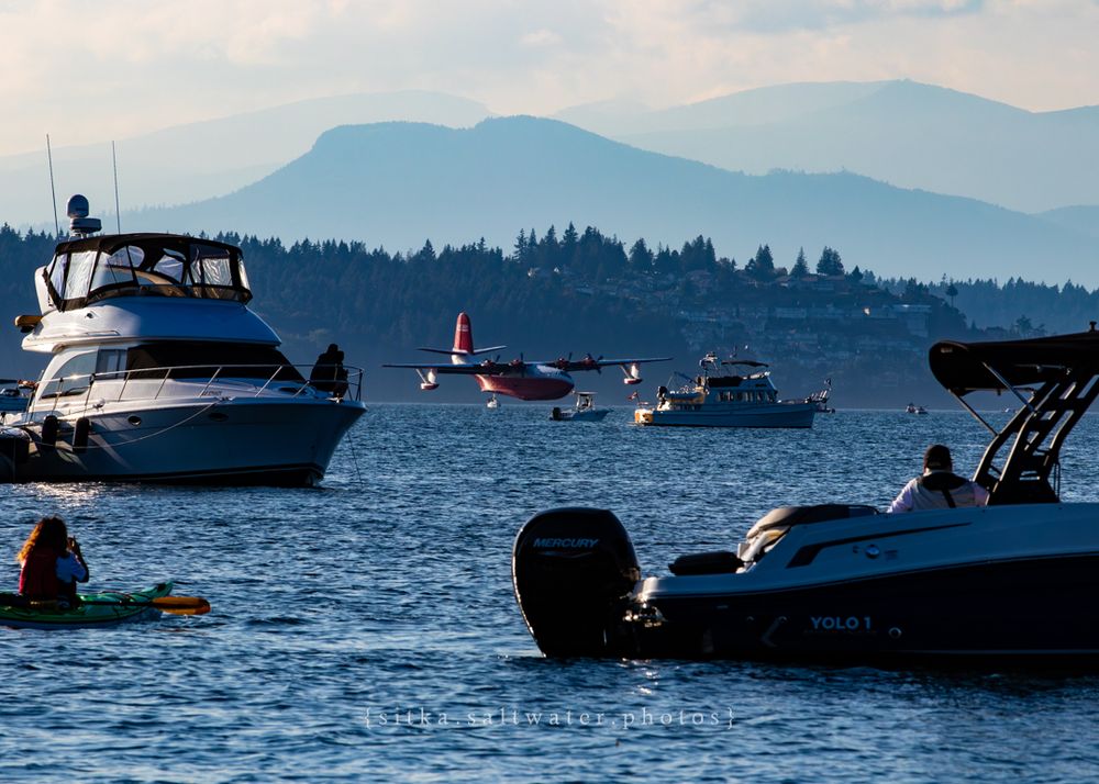 Hawaii Mars performing water landing among boats with mountain landscape in background.