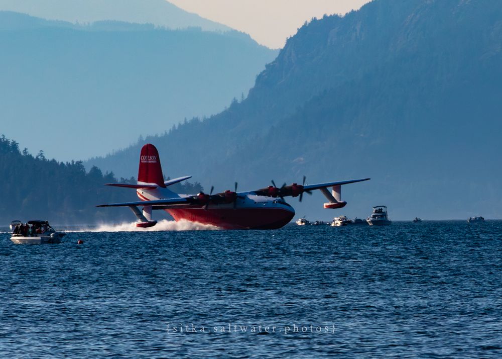 Hawaii Mars skimming across water surface with mountains and boats in background.