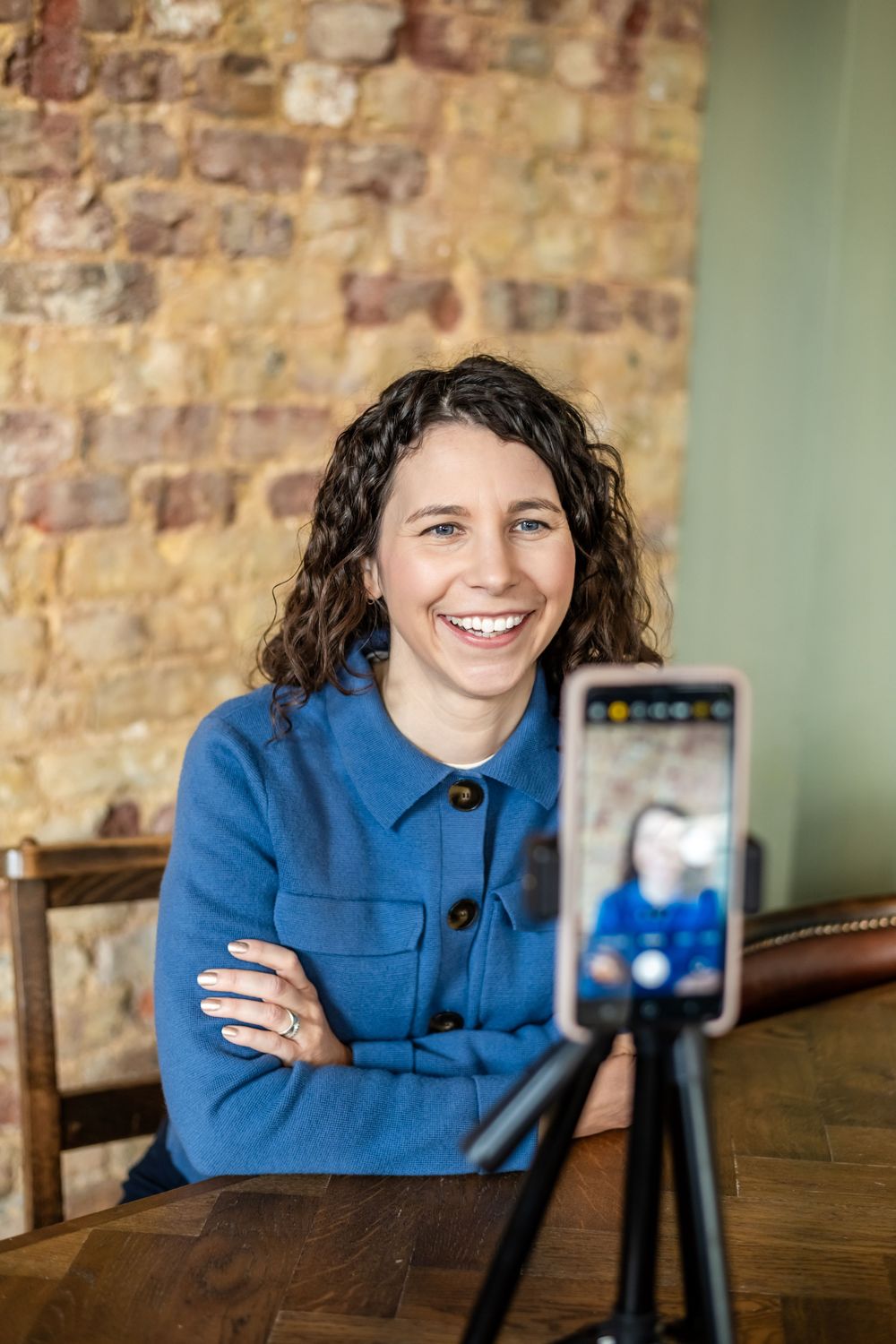 A series of shots showing someone in a bright blue sweater sitting at a wooden table with a camera setup.
