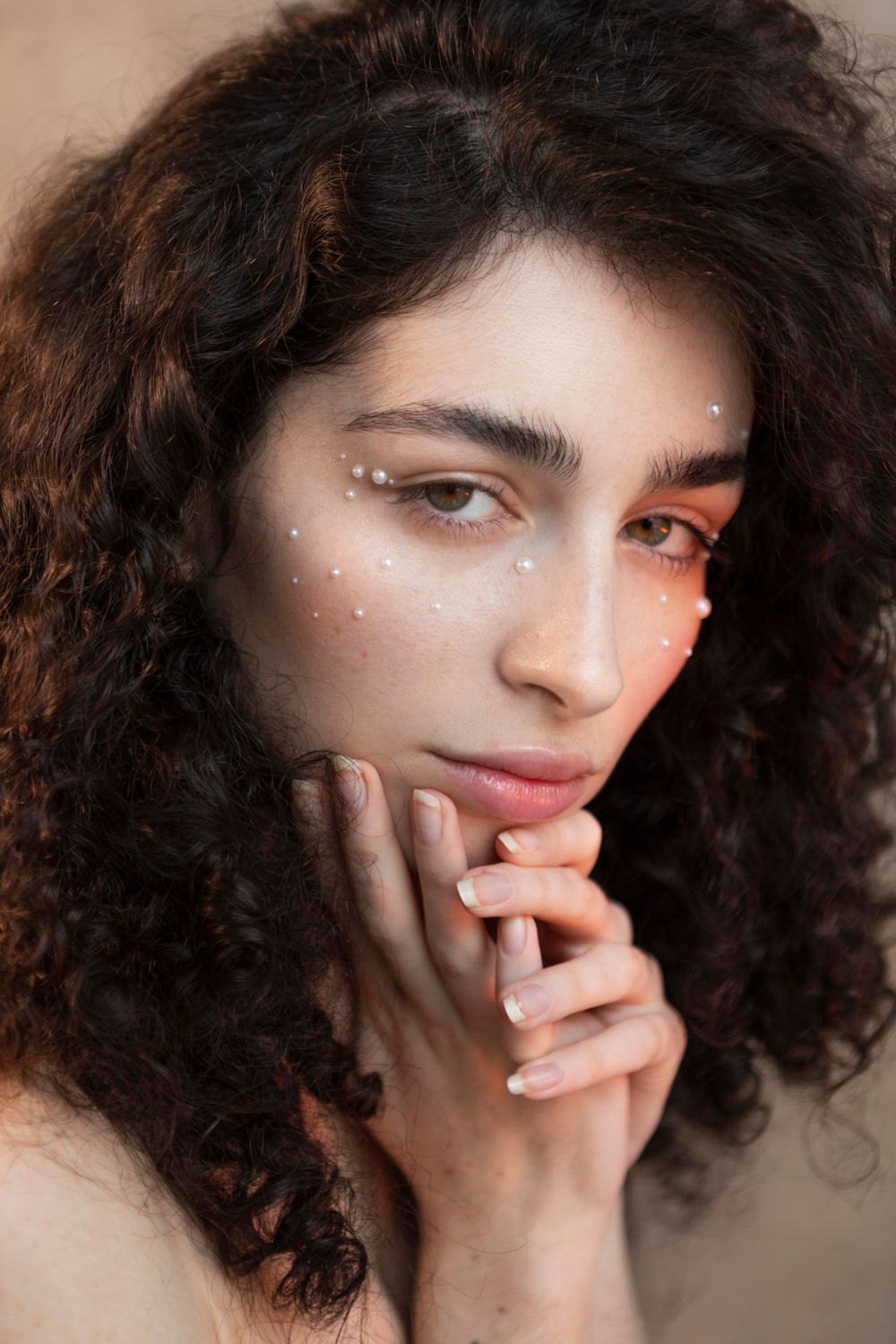 Close-up beauty portrait with sparkly makeup and natural curly hair.