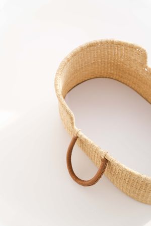 A tan woven fabric or leather belt with a round metal loop buckle on white background.