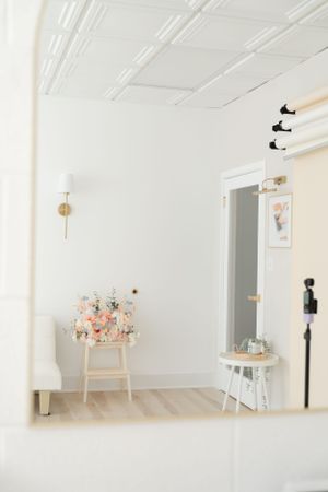 Minimalist white interior space with pink floral arrangement on chair and decorative black birds on wall.