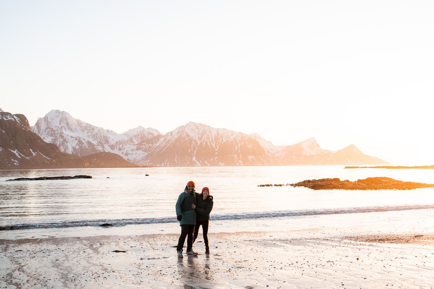 couple voyage au coucher de soleil à haukland beach en hiver