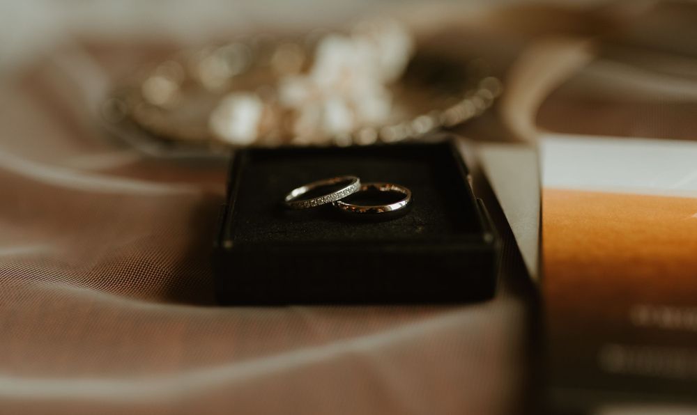 Two silver wedding bands displayed in black velvet ring box on satin fabric.