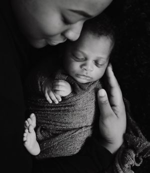 Intimate black and white portrait of tender moment with wrapped newborn.