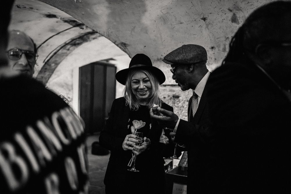 People enjoying drinks and conversation in a dimly lit cellar bar with stone archways.