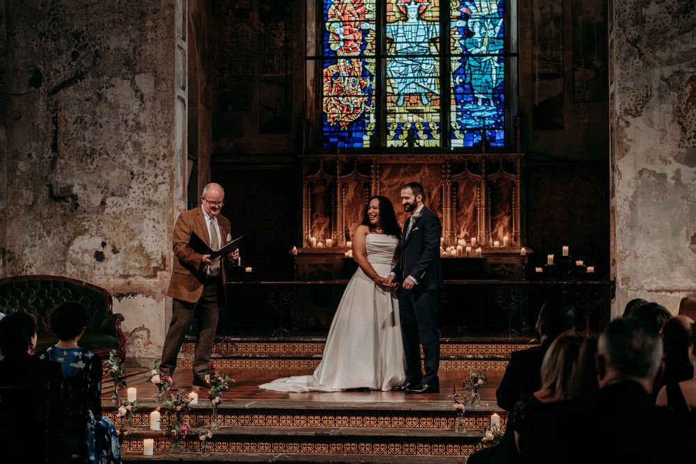 Gothic church interior with stained glass windows and stone walls during a wedding ceremony.