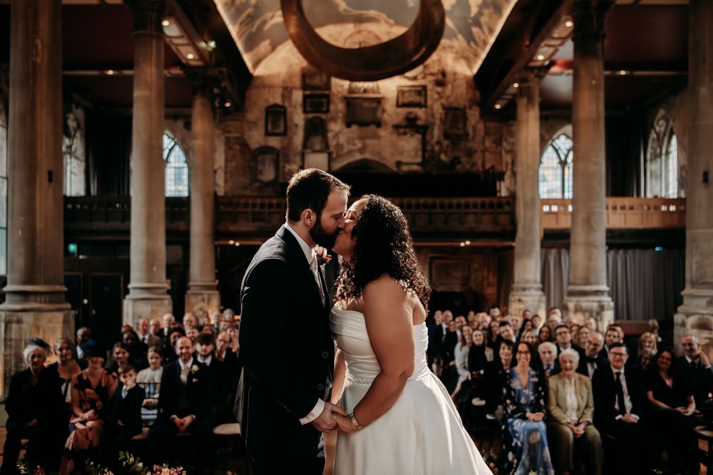 A bride and groom share their first dance in an elegant ballroom surrounded by wedding guests.