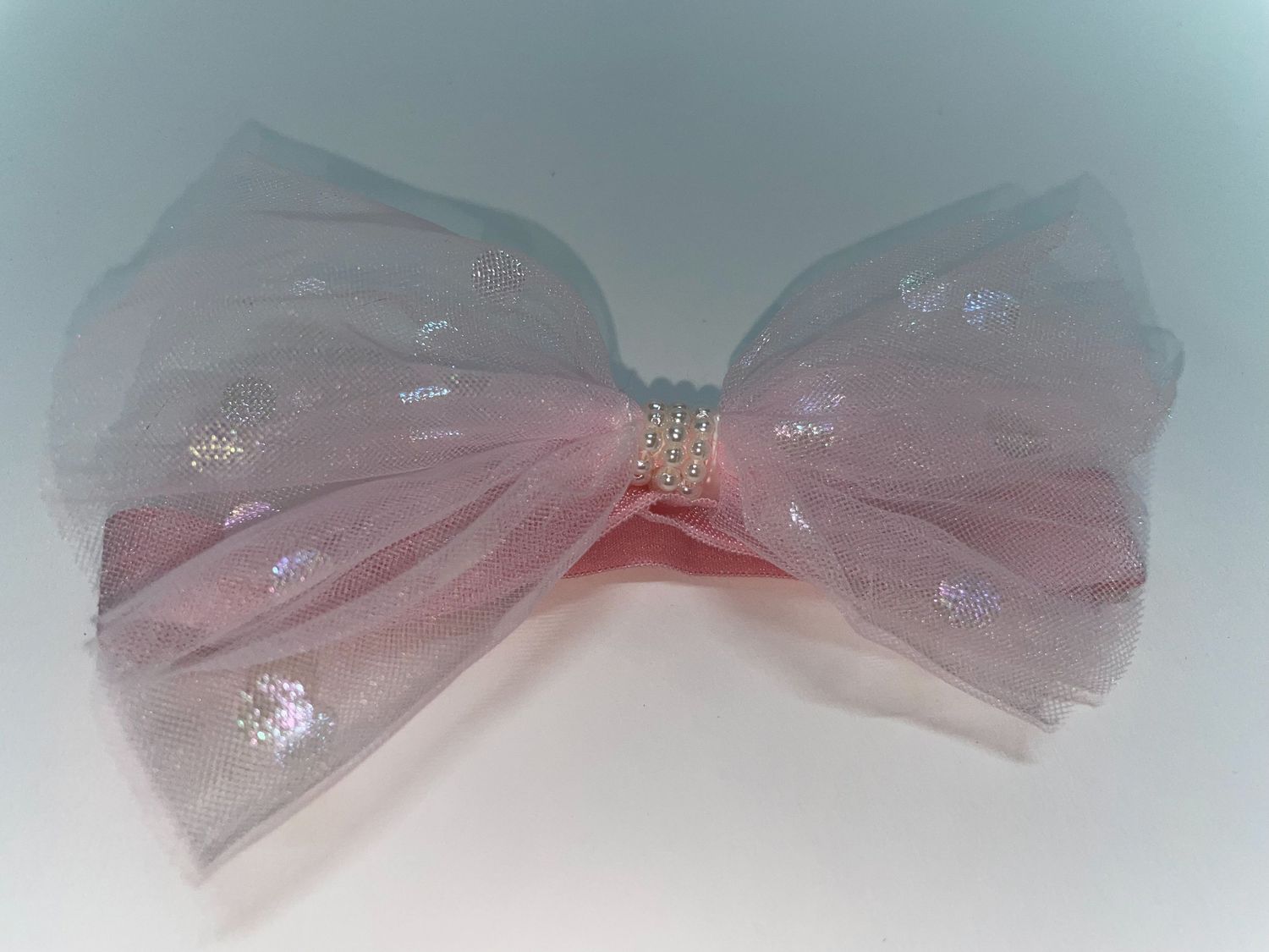 A delicate pink tulle bow with shimmering details.