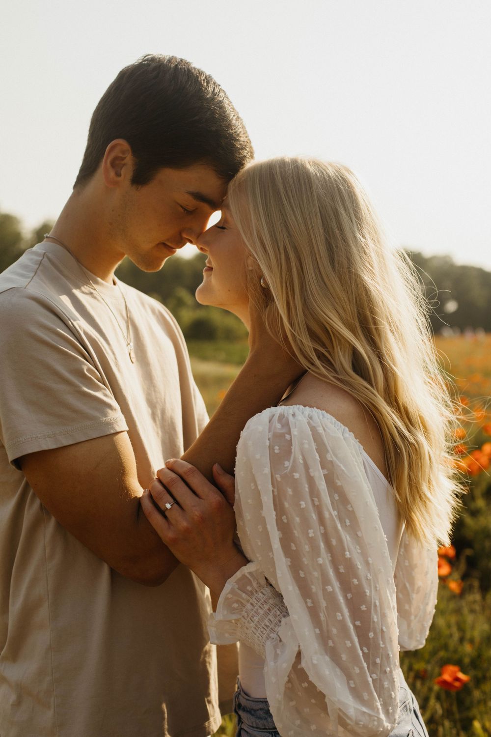 Romantic couple embracing in a golden flower field at sunset.