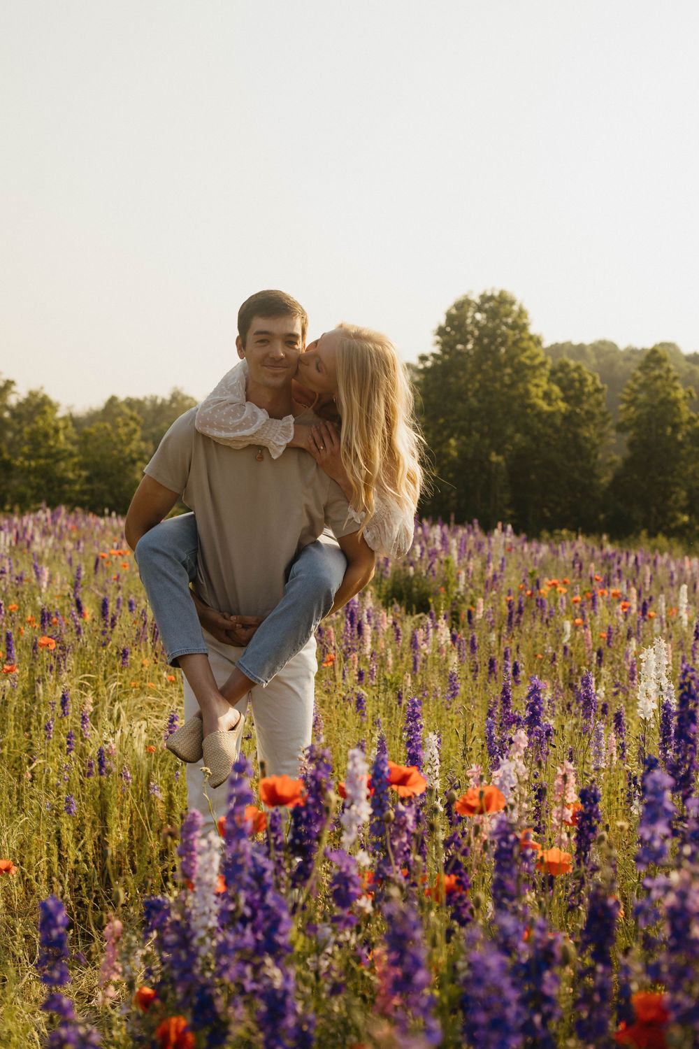 Couple sharing romantic moments among purple and orange wildflowers.