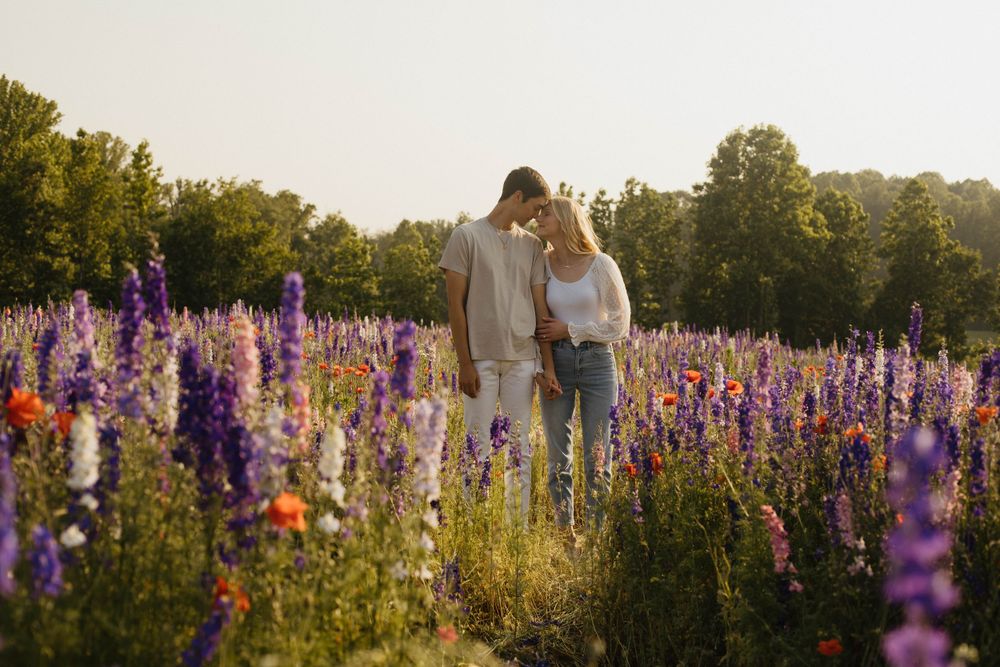Wide landscape view of a couple in a vast field of purple flowers.