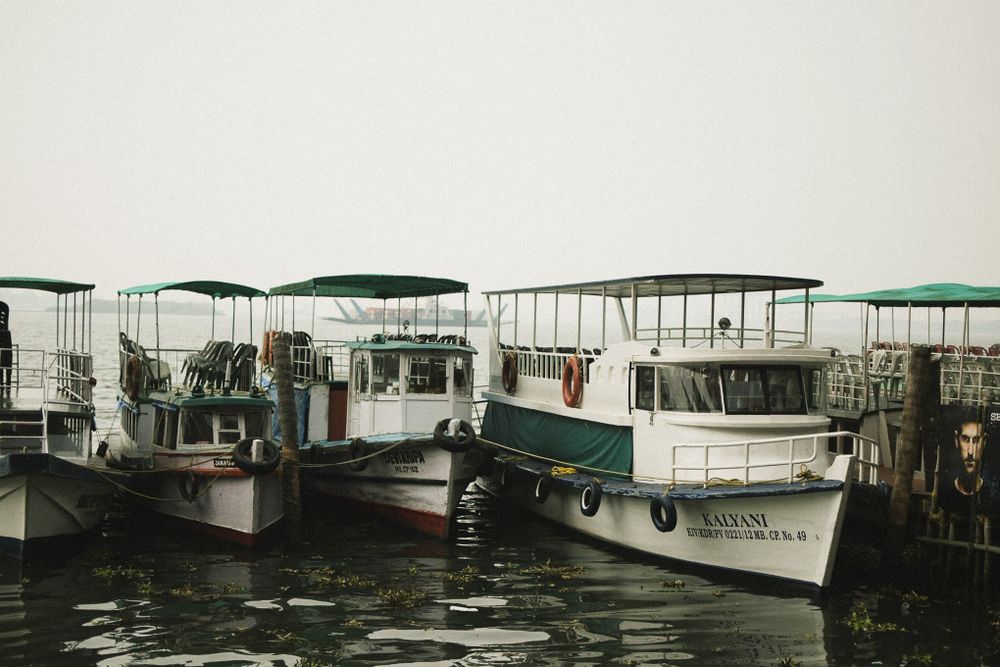 Row of white boats with canopies moored at a dock in black and white.
